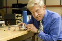 Orest Symko demonstrates a device for a promising new technology for capturing heat now wasted during industrial processes and turning it into electric power. Here, Symko uses a battery to heat the device in his hands. The device changes the heat to audible sound, and then into an electric current that makes the light bulb glow.